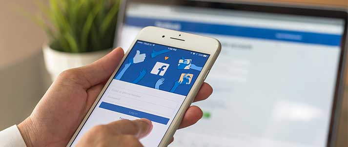 man holding phone with facebook
